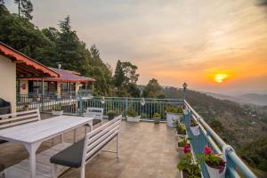 balkon ze stołem, ławkami i zachodem słońca w obiekcie Alpine Rhapsody w mieście Ranikhet