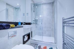 a white bathroom with a shower and a toilet at Luxury 2 bed flat in a new block in East Acton in London
