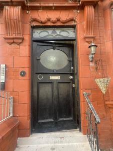 a black door on a red brick building with a street light at Holiday Plus - Holmfield Road in Blackpool