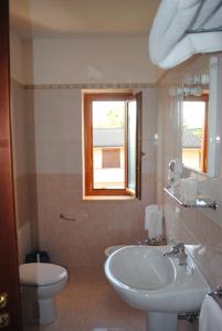 a bathroom with a sink and a toilet and a window at Larus Hotel in Sangineto