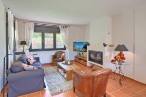 a living room with a couch and a tv at Mooie 6P villa met privézwembad, grote tuin en gratis WiFi in Begur in Begur