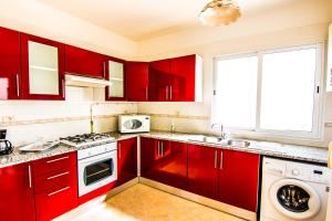 d'une cuisine avec des placards rouges, un évier et une fenêtre. dans l'établissement Mahdia Place Apartments, à Mahdia