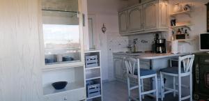 eine Küche mit weißen Schränken und einer Theke mit Stühlen in der Unterkunft Sylter Spatz in Westerland
