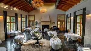 un restaurant avec des tables et des chaises blanches et un lustre dans l'établissement Landgoed Altenbroek, à Fourons