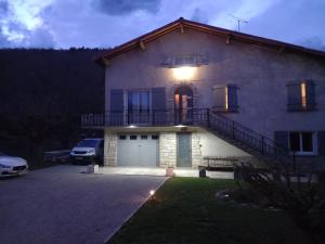 een huis met een balkon en 's nachts een garage bij chambre d'hôtes Ô rendez-vous in Roquefeuil