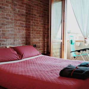 - une chambre avec un lit rouge et un mur en briques dans l'établissement Bikefriendly 70 via degli Dei, à San Piero a Sieve