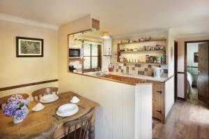 a kitchen with a wooden table with chairs and a counter at Y Caban at Wig Farm near Llangrannog in Llandysul