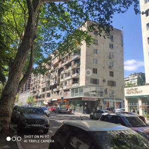 un grand bâtiment sur une rue de la ville avec des voitures garées dans l'établissement apartment, à Tbilissi