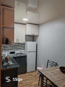 Il comprend une cuisine équipée d'une table et d'un réfrigérateur blanc. dans l'établissement apartment, à Tbilissi
