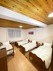 een kamer met 3 bedden en een houten plafond bij Shkodra Guest House in Shkodër