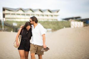 mężczyzna i kobieta spacerujący po plaży w obiekcie Boutique Hotel Blendin Bloemendaal aan Zee w mieście Overveen