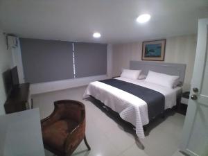 1 dormitorio con 1 cama y 1 silla en Hotel Ejecutivo Portoviejo, en Portoviejo