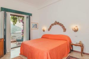 a bedroom with an orange bed and a balcony at Hotel Poseidon in Positano