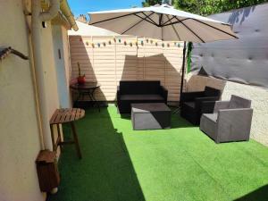 a patio with green grass and an umbrella at Maison T2 proche mer jardin et parking securise in Six-Fours-les-Plages