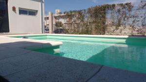 una piscina con acqua turchese accanto a un edificio di Casa Amplia, Luminosa con Quincho y Pileta! a Tandil Altre 11 foto