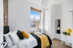 a white bedroom with a bed with a window at Central Hackney Abode - Balcony in London