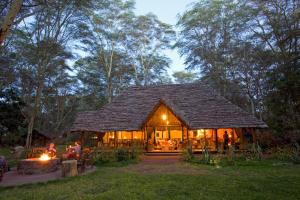 a hut with people sitting in the yard at night at Migunga Tented Camp in Mto wa Mbu