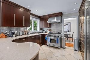 a kitchen with brown cabinets and a stove top oven at Large & Sunny Private bedroom in Villa in Toronto