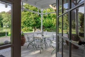 un porche cubierto con mesa y sillas en Landgoed Altenbroek, en Voeren