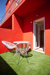 twee stoelen en een tafel voor een rood gebouw bij Campolide Charm Apartments in Lissabon