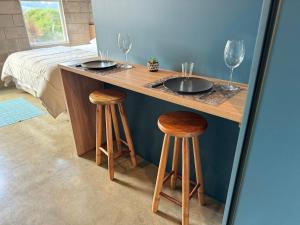 a wooden counter with two wine glasses and two stools at Studios in Serra Negra