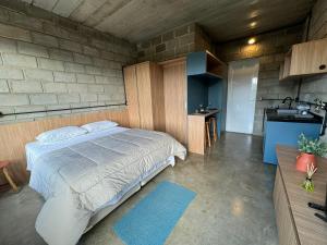a bedroom with a large bed and a kitchen at Studios in Serra Negra