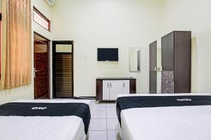 a room with two beds and a tv in it at Capital O 93204 Hotel Mulia Dua Syariah in Klaten