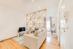 a living room with a white couch and a tv at Campolide Charm Apartments in Lisbon