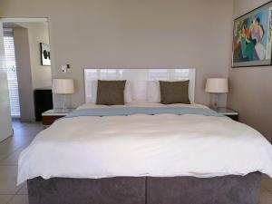 a large white bed in a bedroom with two lamps at 'Antilles'- 6 Bedroom Luxury Villa On The Beach, Sleeps 12 in Gordonʼs Bay