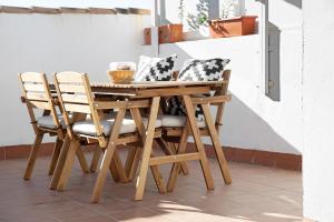 een houten tafel en stoelen met kussens erop bij Villa Maria in Chipiona