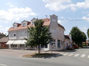 a white house with a tree in front of a street at Guest House Talas in Osijek