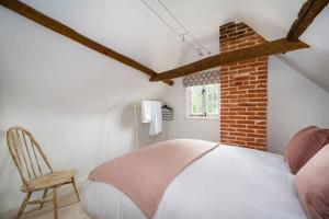 Dragonfly Cottage, Long Melford في لونغ ميلفورد: غرفة نوم بسرير ابيض وكرسي
