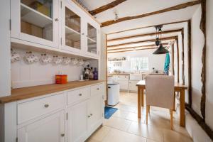 Dragonfly Cottage, Long Melford في لونغ ميلفورد: مطبخ مع دواليب بيضاء وطاولة طعام