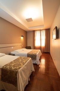 um quarto de hotel com duas camas e uma janela em Serrano Residencial Hotel em Juiz de Fora