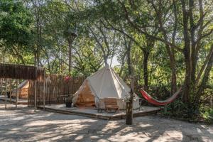 a tent with a hammock next to a fence at Glamping Coco Dendê - Algodões in Praia dos Algodões