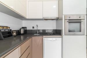 una cocina con armarios blancos y electrodomésticos de acero inoxidable en Comfy Residence Flat 3 min to Mall of Antalya, en Antalya