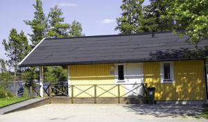 uma casa amarela e branca com um telhado preto em Årsunda Strandbad em Årsunda
