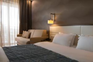 une chambre d'hôtel avec un lit et un canapé dans l'établissement Cosmopolitan Hotel & Spa, à Paralia Katerinis