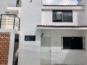 een wit huis met een deur en een raam bij El Depa del Puerto in Cancun