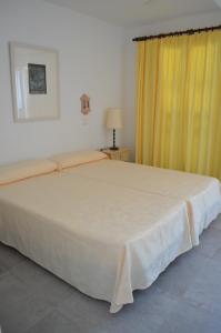a bedroom with a large bed with a yellow curtain at Apartamentos Parque Mar in Cala d´Or