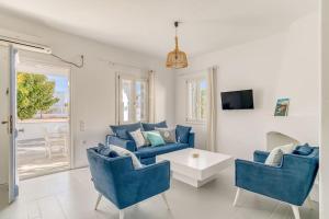 sala de estar con sofá azul y sillas en Sand And Seas: Villa Asterias, en Ampelas