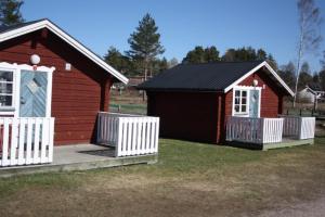 Twee kleine schuren met een wit hek in een tuin. bij Årsunda Strandbad in Årsunda