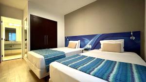 a bedroom with two beds and a blue headboard at QSA - Anora Spaces - Metropolis Alphaville in Barueri