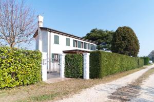 una casa blanca con un seto al lado de una carretera en Casa Battaglia, en Cavallino-Treporti