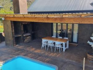 una terraza de madera con mesa y sillas junto a una piscina en Oorlogs Kloof Mountain Retreat Montagu en Montagu