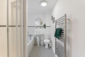 La salle de bains blanche est pourvue d'un lavabo et de toilettes. dans l'établissement Designer Apartment - Great Location!, à Manchester