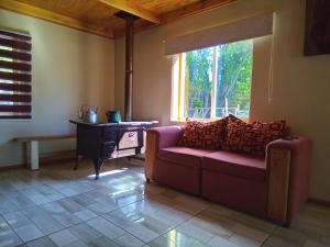 ein Wohnzimmer mit einer Couch und einem Tisch und einem Fenster in der Unterkunft Cabaña los sauces in Chile Chico + 16 Fotos
