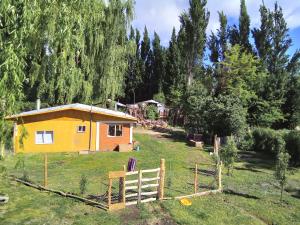 a small yellow house in the middle of a field at Cabaña los sauces in Chile Chico