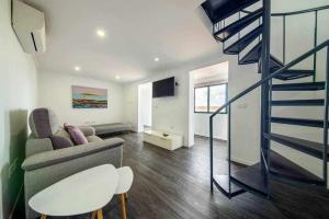 ein Wohnzimmer mit einem Sofa und einer Wendeltreppe in der Unterkunft Lombo do Doutor Cottage 1 by Mth in Calheta