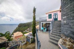 a pink house with stairs leading to the ocean at Lombo do Doutor Cottage 1 in Calheta